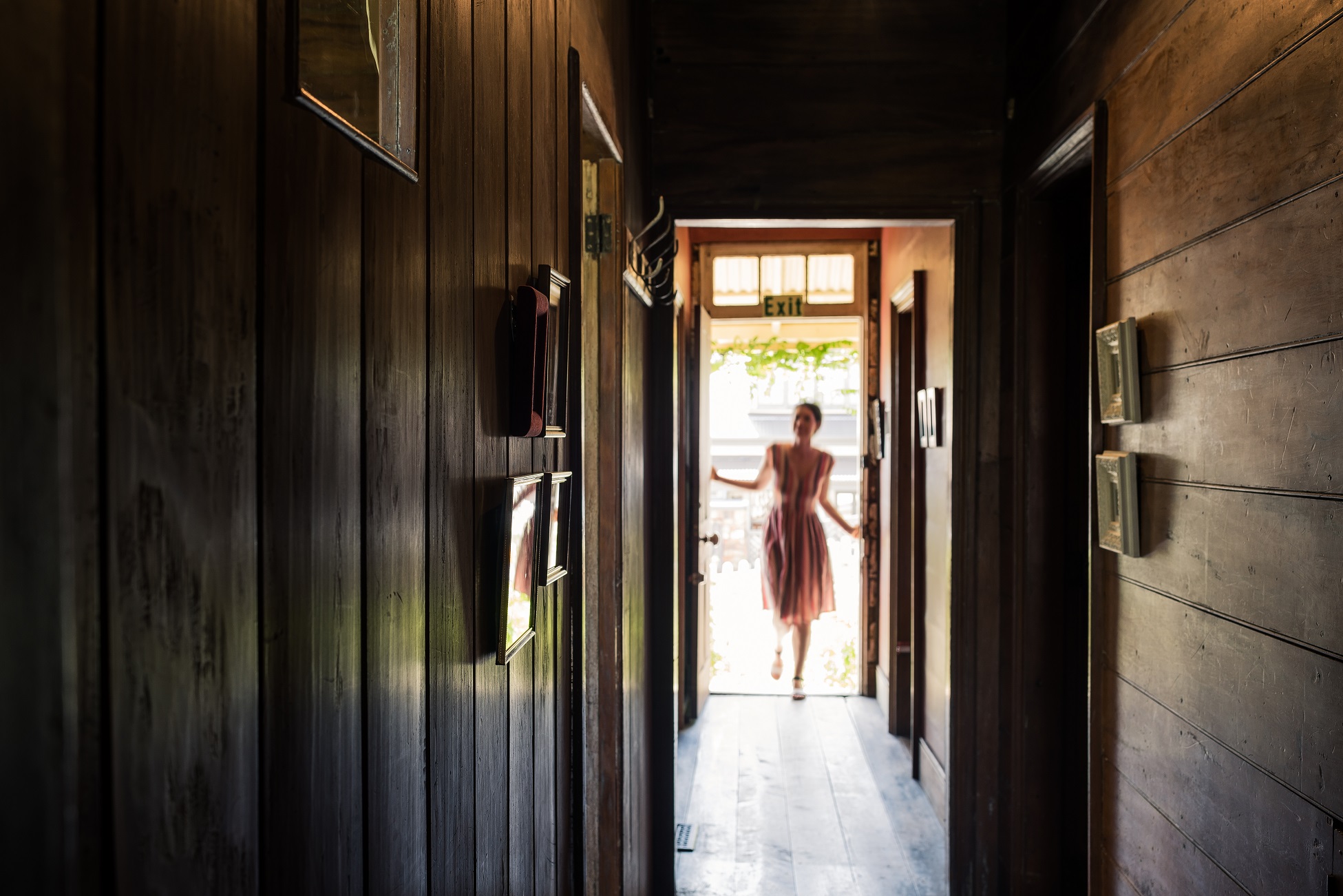A long shot through the cottage's corridor as a woman enters through the front door.
