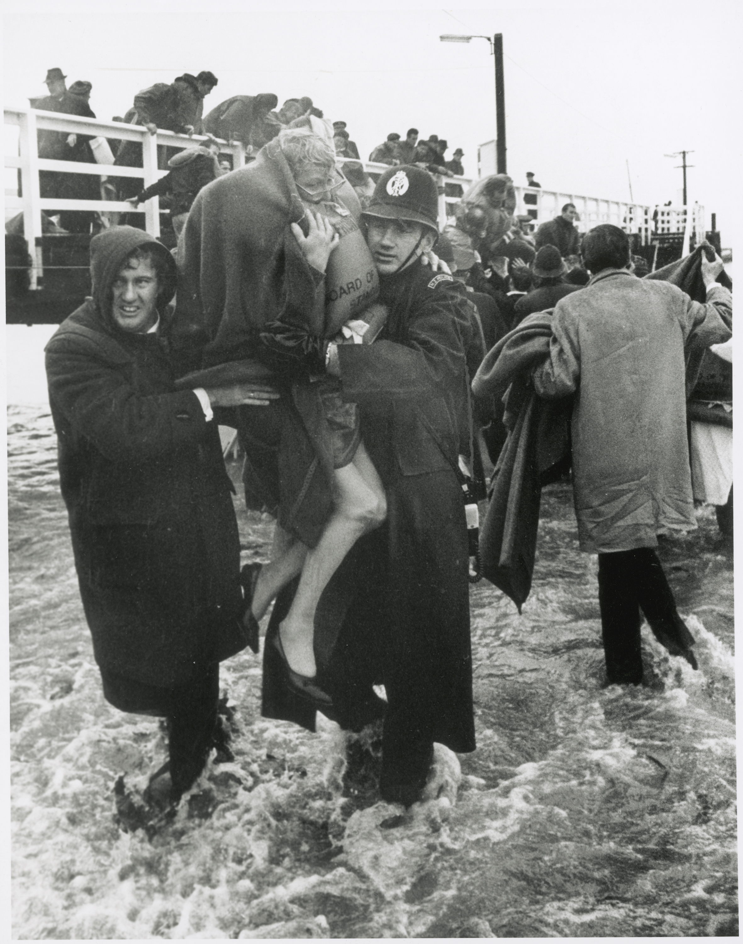 Policeman and other man assisting female survivor from "Wahine", Seatoun Wharf